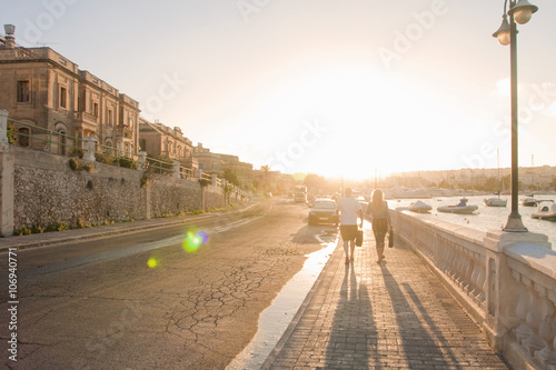 Couple strolling along harbor at sunset, Ta' Xbiex, Gzira, Malta photo