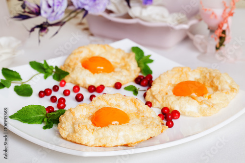 pastry with egg yolk, air biscuits, beaten white, berry, plate
