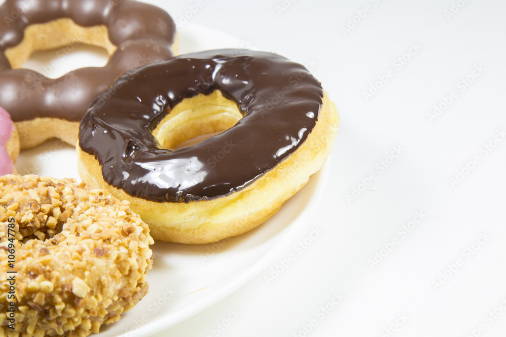 Donut glazed chocolate strawberry peanut on white dish on backgr Donut glazed chocolate strawberry peanut on white dish on backgr