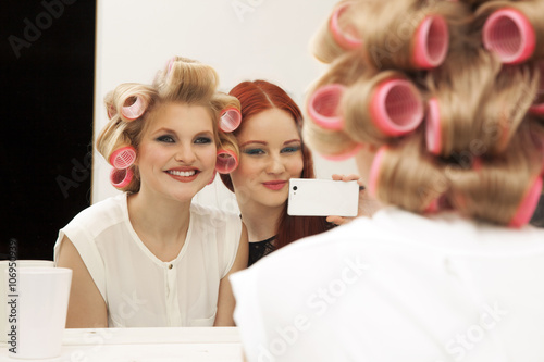 Young woman in curlers and friend taking selfie