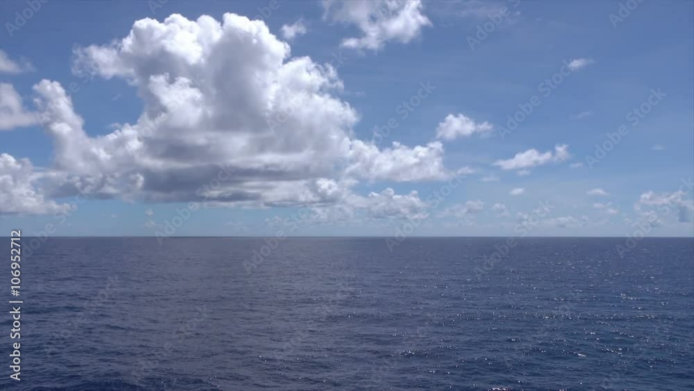 Blue sky, clouds and tranquil water at sea with horizon, pan Blue sky, clouds and tranquil water at sea with horizon, pan