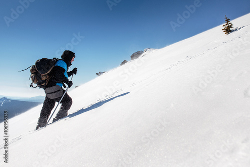 A male climber , in full gear and equipment, climbs up a snowy s photo