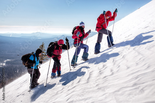 group of climbers climb the steep slopes of the snow-capped mountains on a clear day