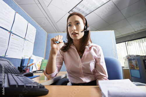 Young female office worker talking on headset in office