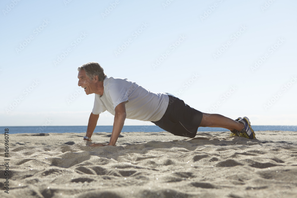 Senior man doing push ups on beach Senior man doing push ups on beach
