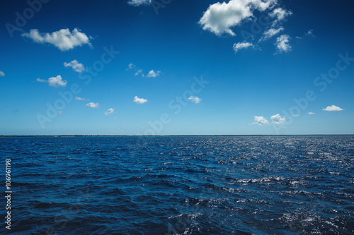 Fototapeta Naklejka Na Ścianę i Meble -  White fluffy clouds blue sky above a surface of the sea