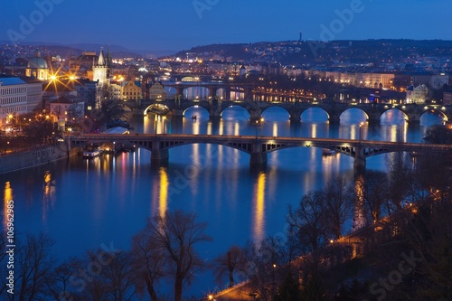 Evening Picture over Prague bridges and riverbank on the Vltava river with Charles bridge included in twilight during the blue hour. Historical downtown of Prague, capital of Czech Republic in Europe.