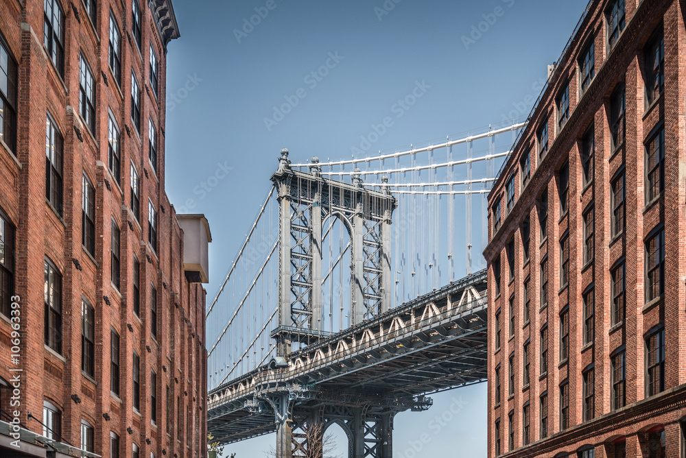 Naklejka premium Manhattan most widzieć od wąskich budynków na słonecznym dniu