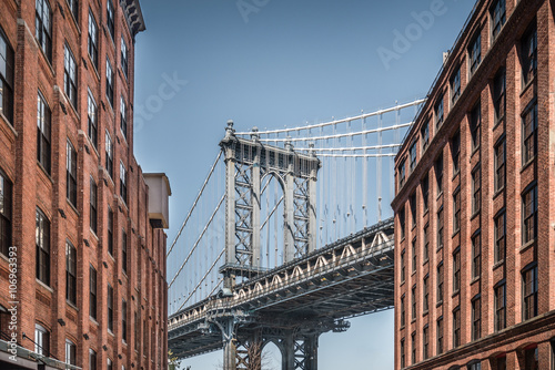 Fototapeta Naklejka Na Ścianę i Meble -  Manhattan bridge seen from narrow buildings on a sunny day