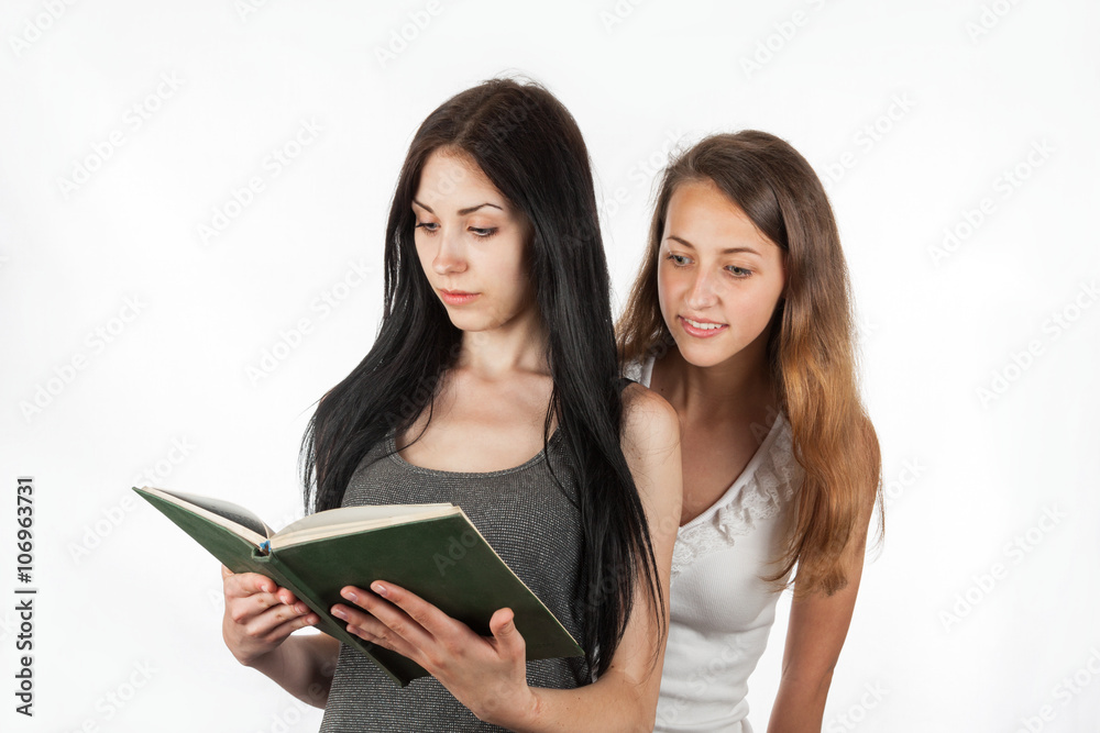 Beautiful girl peeping into girlfriend's book Beautiful girl peeping into girlfriend's book
