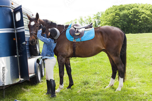 Horse rider putting on horse's bridle photo