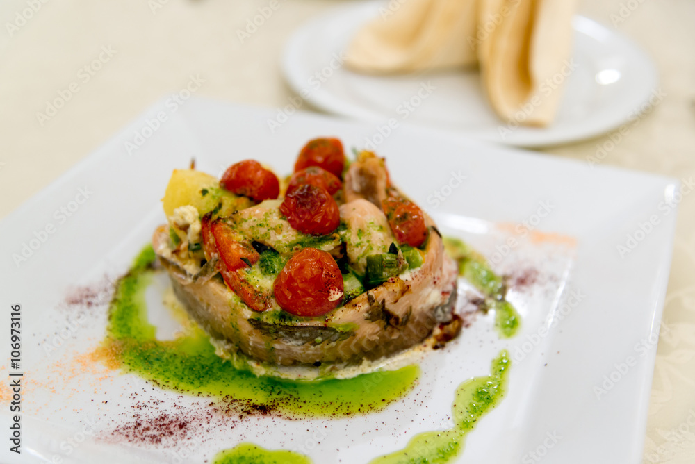 Fish baked with potatoes and tomatoes