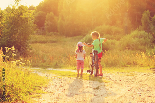 Cute little girls playing at sunny field on summer day