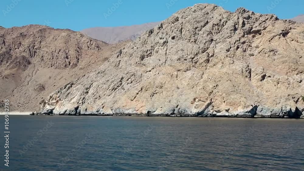 Ship sails along Musandam peninsula, Sultanate of Oman, Gulf of Oman. Oman - arab country in southeastern coast of the Arabian Peninsula. Musandam - governorate of Oman, located on Musandam peninsula Ship sails along Musandam peninsula, Sultanate of Oman, Gulf of Oman. Oman - arab country in southeastern coast of the Arabian Peninsula. Musandam - governorate of Oman, located on Musandam peninsula