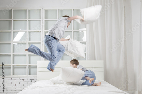 Young children playing on the bed. Pillow fight