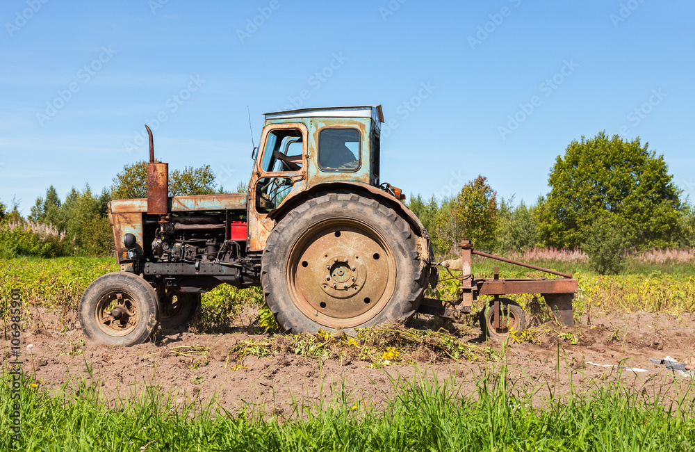 Old wheeled agricultural tractor used at the potato field Old wheeled agricultural tractor used at the potato field