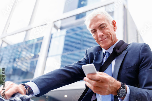 Fotografía Successful businessman on bicycle with mobile phone