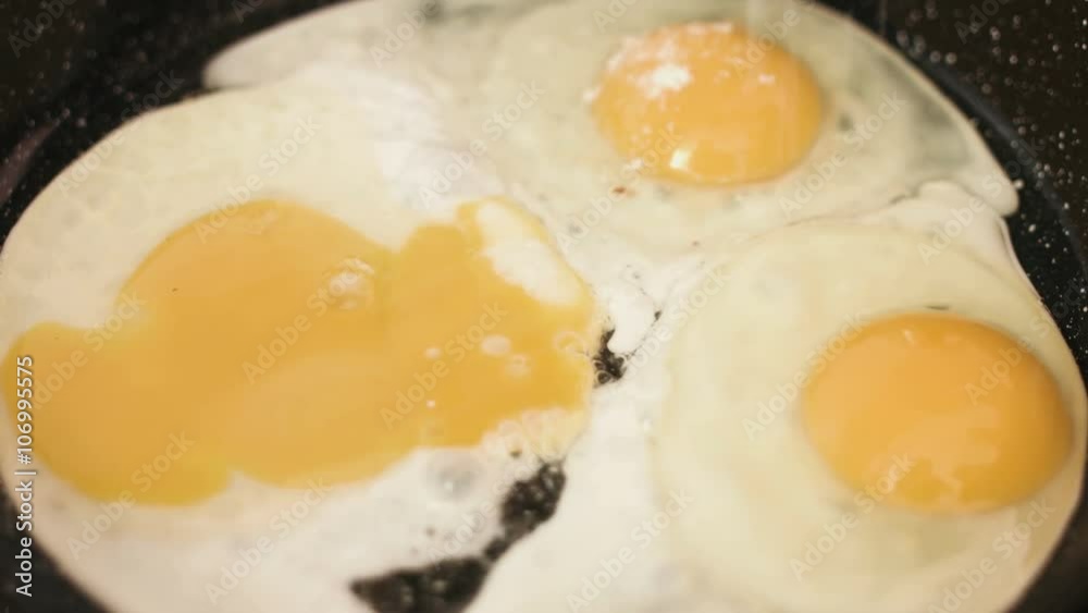 Three fried eggs preparing on a cast-iron frying pan and treated with a salt. Three fried eggs preparing on a cast-iron frying pan and treated with a salt.
