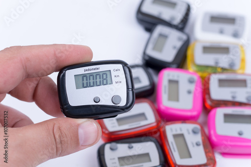 Digital pedometer in the hand over pile of pedometers photo