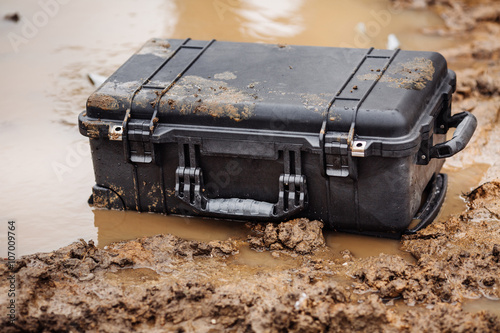 Closed plastic protector case lying  on the water and dirt photo