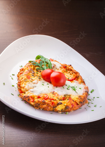 Omelette with cheese tomato ham and rucola plate on wooden table