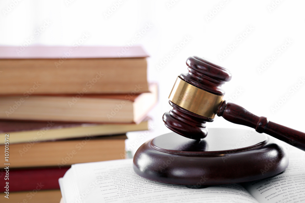 Gavel with pile of books on light blurred background