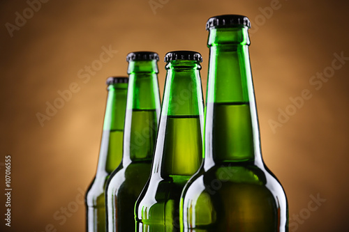Four green glass bottles of beer on dark lighted background  close up