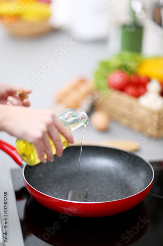 Human hands with oil and frying pan on stove, closeup