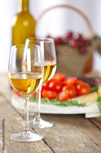 Glasses of wine with food on wooden table closeup