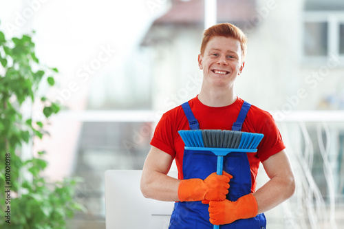 Young janitor holding floor...