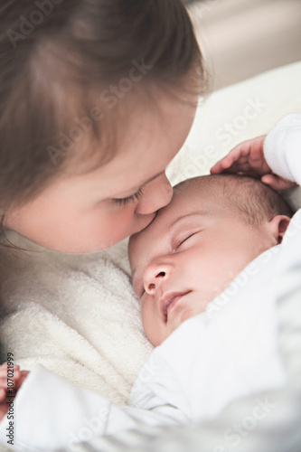 Big sister kissing her newborn brother