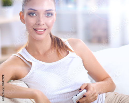 Young beautiful woman sitting on couch at her room using phone photo