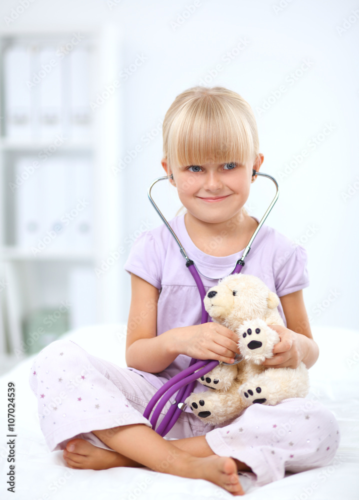 Little girl is examining her teddy bear using stethoscope Little girl is examining her teddy bear using stethoscope