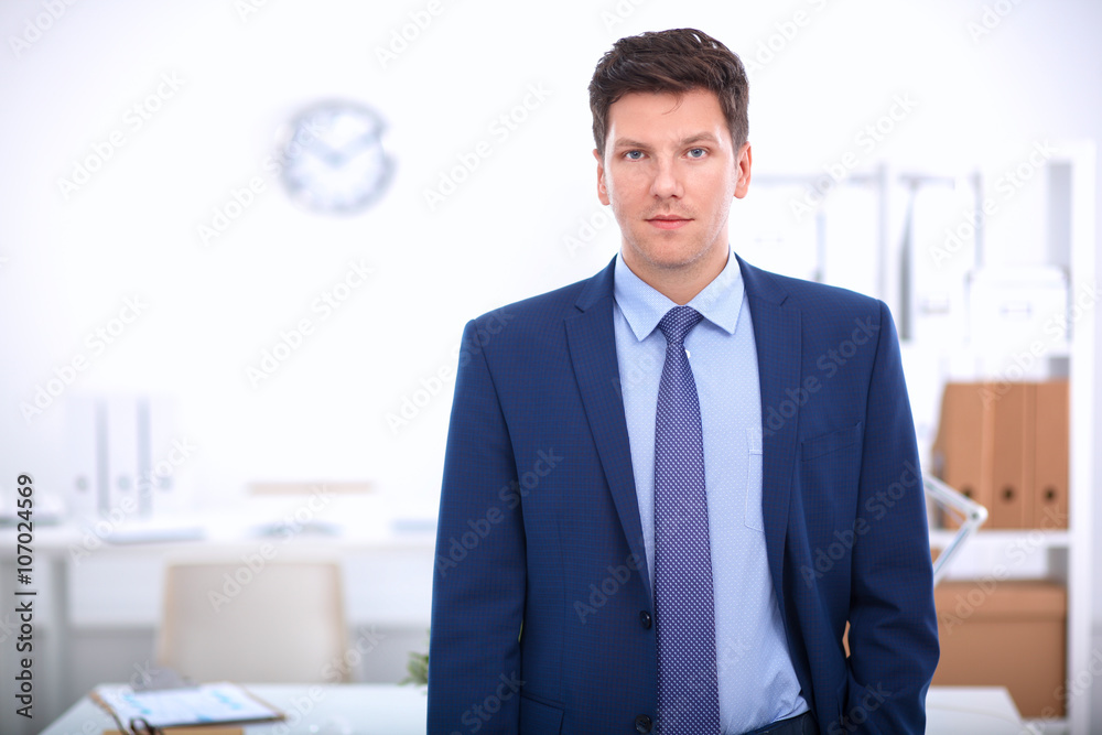 Business man or manager standing against his desk at the office Business man or manager standing against his desk at the office