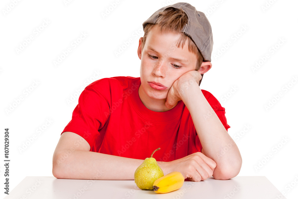 Morose young boy staring at a ripe banana and pear Morose young boy staring at a ripe banana and pear