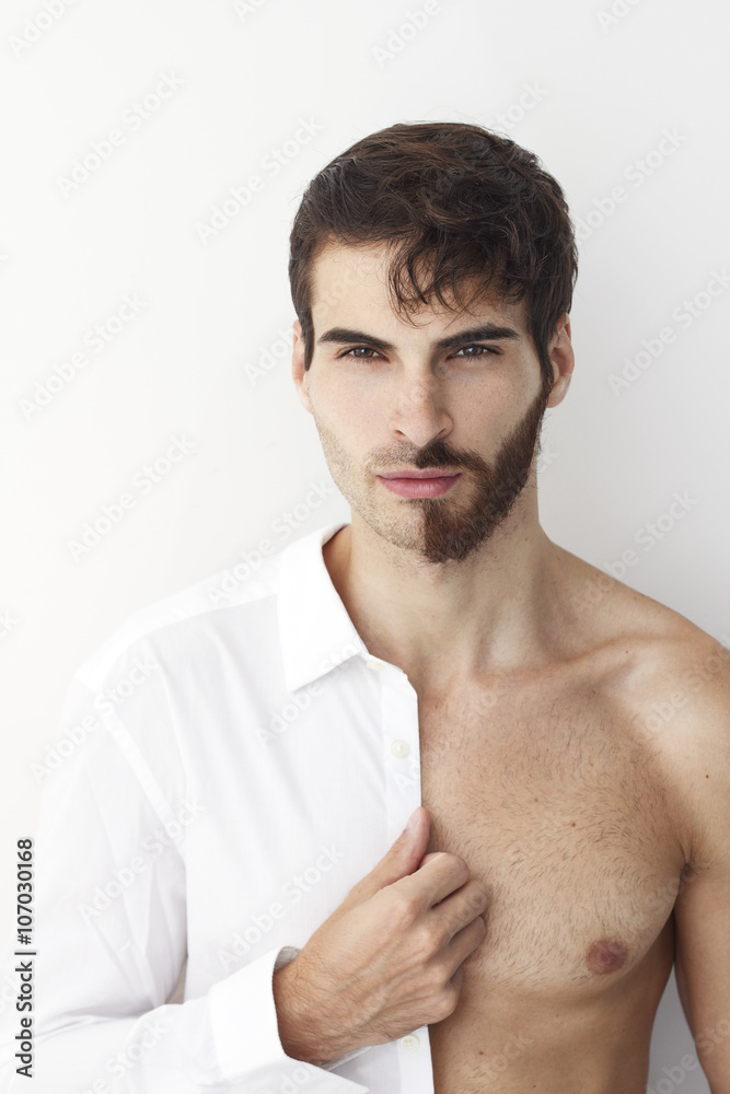 Φωτογραφία Man half dress in white shirt, standing in front of a camera on a white background with half of his face with scruffy beard and messy hair, the other half has trimmed beards