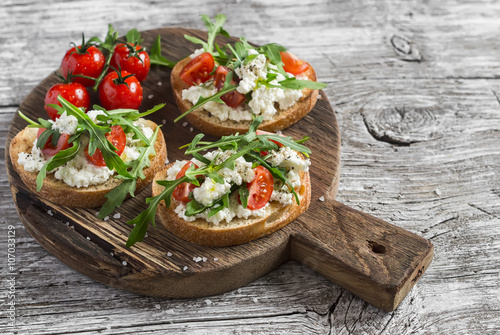 Sandwiches with cheese, tomatoes and arugula on a rustic wooden board. Healthy food