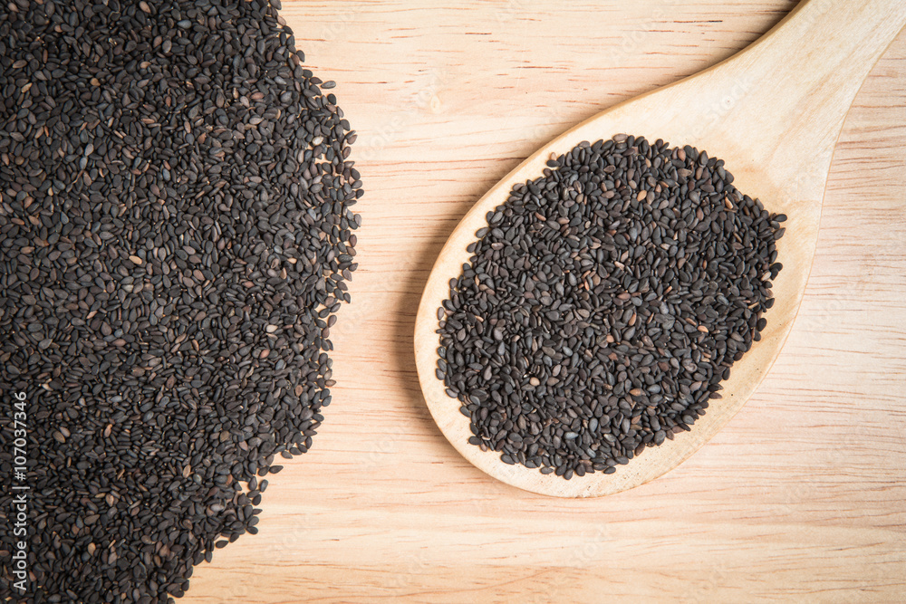 scoop of black sesame and a pile of black sesame on a wooden bac scoop of black sesame and a pile of black sesame on a wooden bac