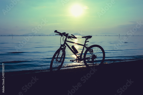 Silhouette of bicycle on the beach against colorful sunset
