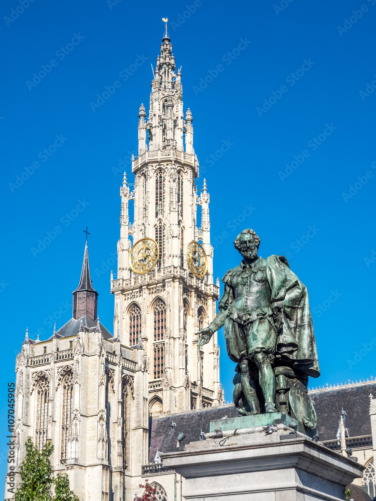 Statue of Peter Paul Rubens with Cathedral of Our Lady in Background in Antwerp, Belgium, under clear blue sky. The cathedral is the highest church in the Benelux with 123 m (404 ft) of height.