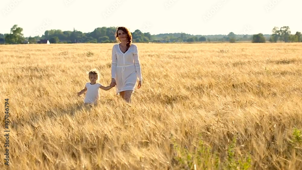 daughter mother go on the field with ears in the evening in summer. slowmotion daughter mother go on the field with ears in the evening in summer. slowmotion
