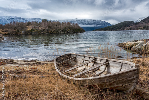 Canvas-taulu Old boat on the shore by a Norwegian fjord