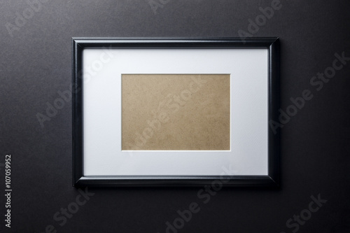 Black thin plain empty wood picture frame with white mat passe-partout on black wall background