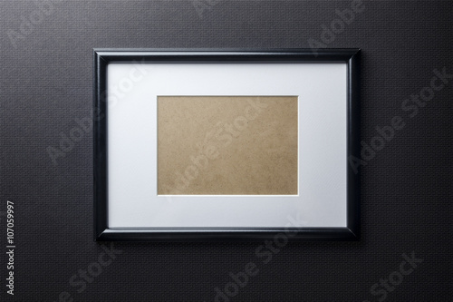 Black plain empty thin wood picture frame with white mat passe-partout on black bricks background