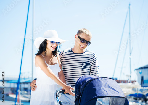Young and attractive couple walking with a baby pram outdoor.