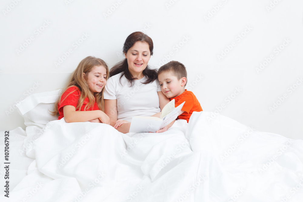 mom reading a book in bed for her childs before sleep