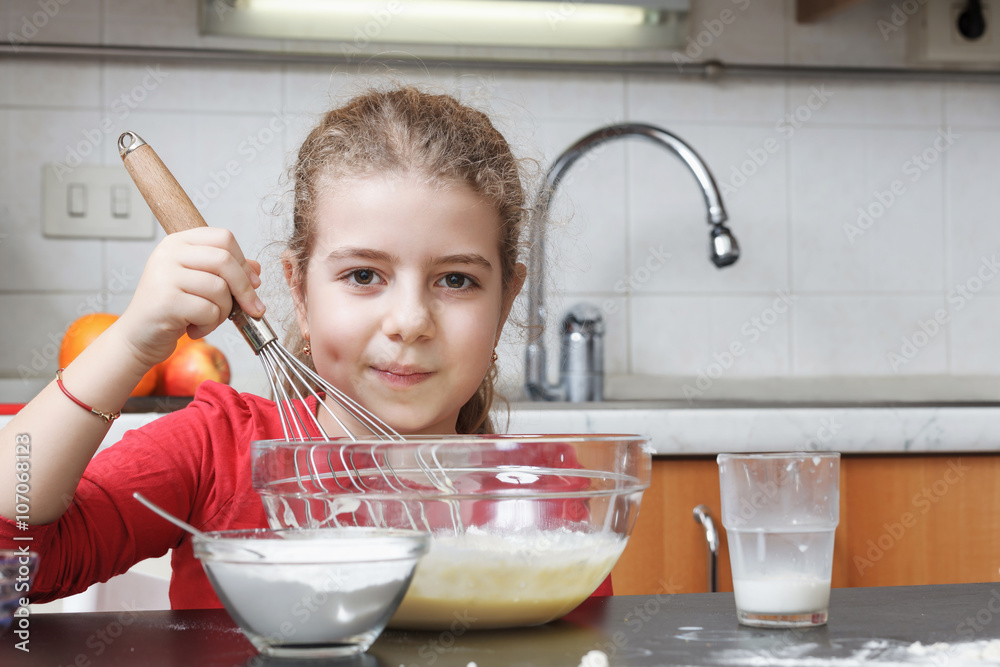 girl in the kitchen making dough mixing flour, milk, in a glass bowl