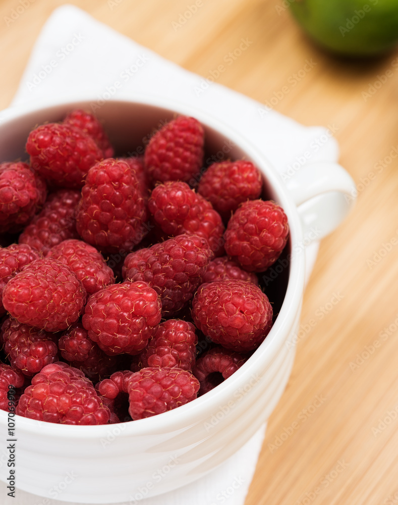 Raspberry in white plate on wooden table, closeup Raspberry in white plate on wooden table, closeup