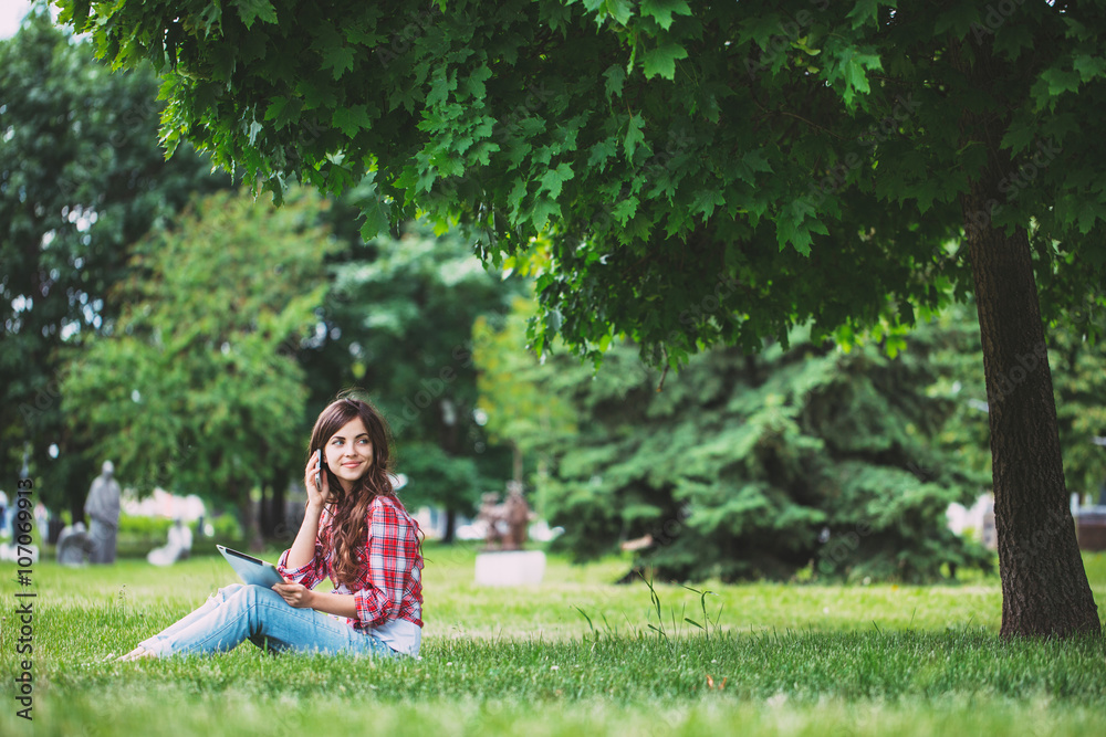 Young beautiful woman talking on the phone in the park. Young beautiful woman talking on the phone in the park.