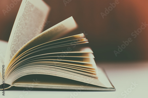 Close up of open book on desk with vintage filter blur background